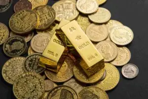 Home 26 monedas de oro y lingotes de oro encima de una mesa negra