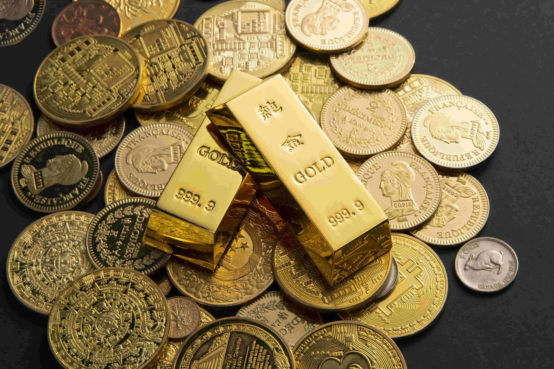 monedas de oro y lingotes de oro encima de una mesa negra